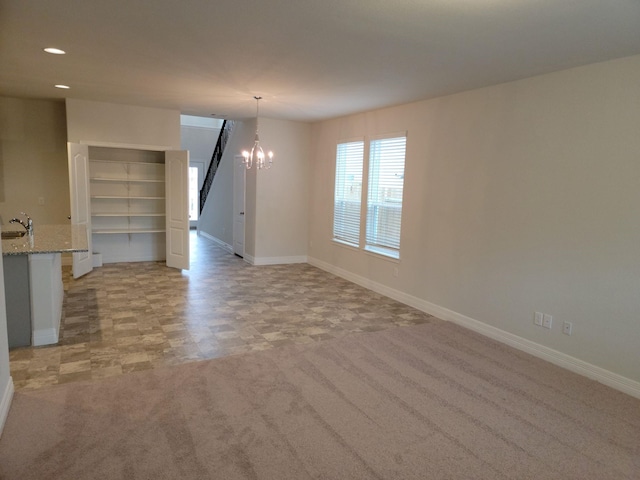 carpeted spare room with sink and a chandelier