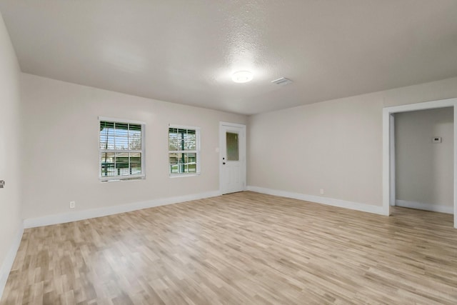 unfurnished room featuring light hardwood / wood-style floors and a textured ceiling