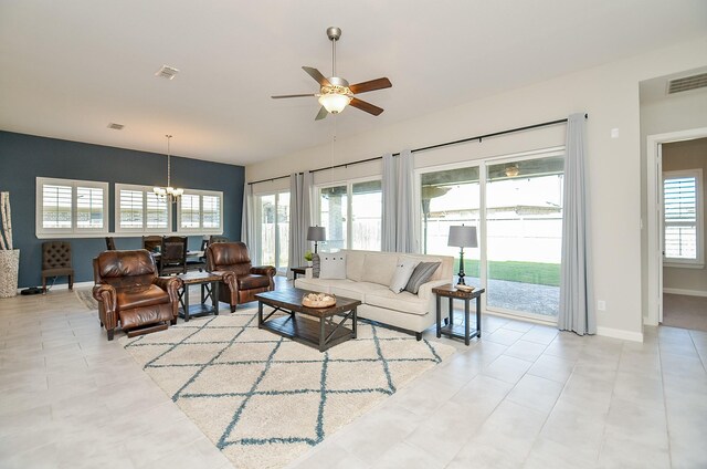 living room with ceiling fan with notable chandelier and light tile patterned floors