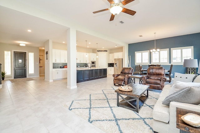 living area with ceiling fan with notable chandelier, baseboards, visible vents, and recessed lighting