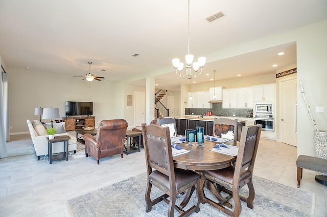 dining space with light tile patterned flooring, recessed lighting, ceiling fan with notable chandelier, visible vents, and stairway