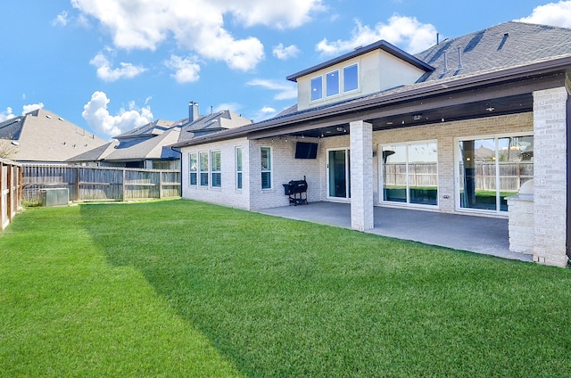 back of property featuring a patio area, a fenced backyard, brick siding, and a yard