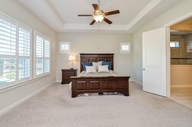 carpeted bedroom with connected bathroom, ceiling fan, and a raised ceiling