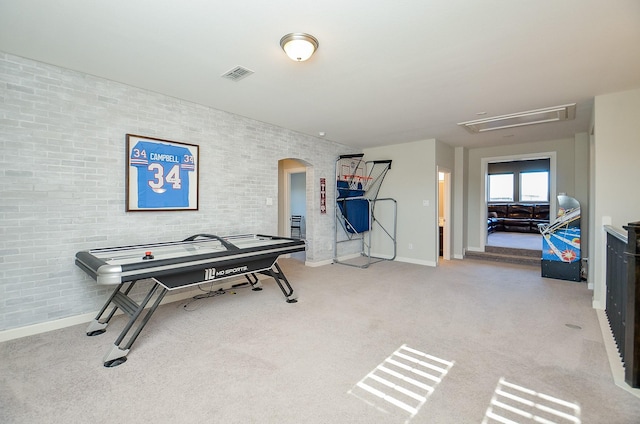 playroom featuring arched walkways, brick wall, visible vents, carpet, and attic access