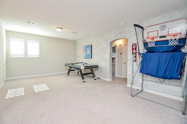 misc room featuring arched walkways, visible vents, carpet flooring, brick wall, and baseboards