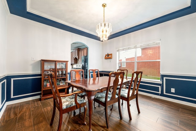 dining room featuring dark hardwood / wood-style flooring, crown molding, and an inviting chandelier