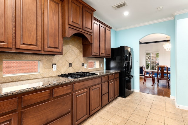 kitchen featuring black appliances, dark stone counters, decorative backsplash, light tile patterned flooring, and crown molding