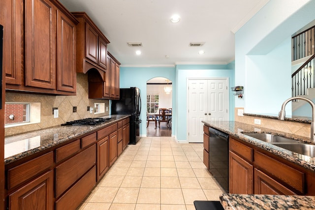 kitchen featuring black appliances, dark stone countertops, sink, ornamental molding, and light tile patterned flooring