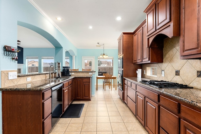 kitchen featuring sink, dark stone countertops, stainless steel appliances, and a healthy amount of sunlight