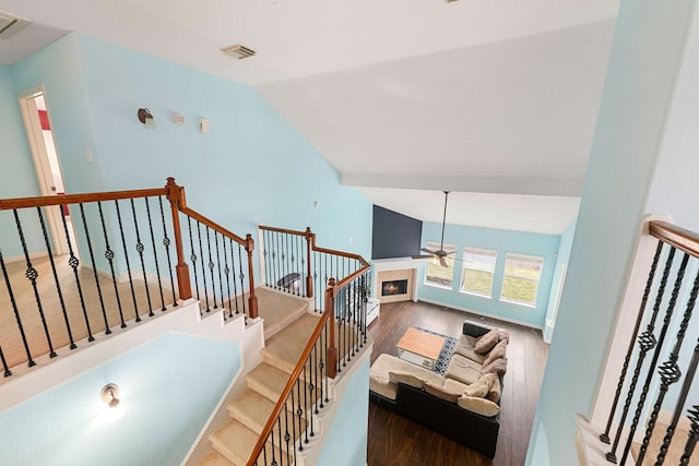 staircase with ceiling fan, hardwood / wood-style floors, and lofted ceiling