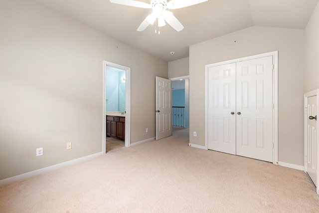 unfurnished bedroom featuring a closet, vaulted ceiling, ceiling fan, light colored carpet, and ensuite bathroom