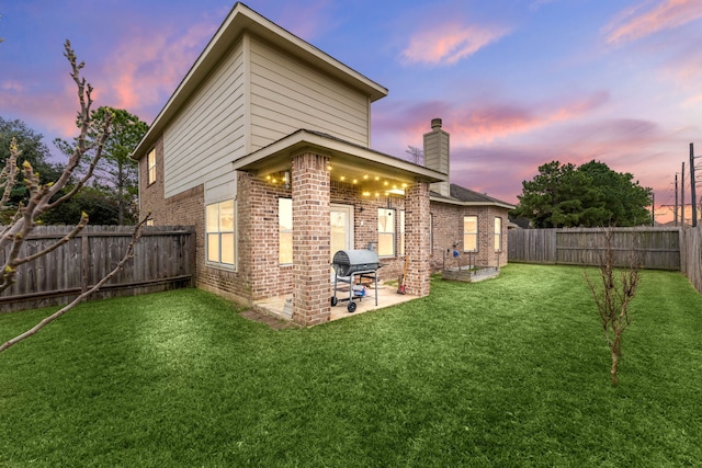 back house at dusk with a yard and a patio