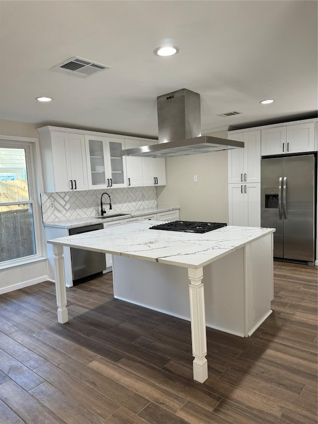 kitchen with island range hood, white cabinets, sink, stainless steel appliances, and light stone counters