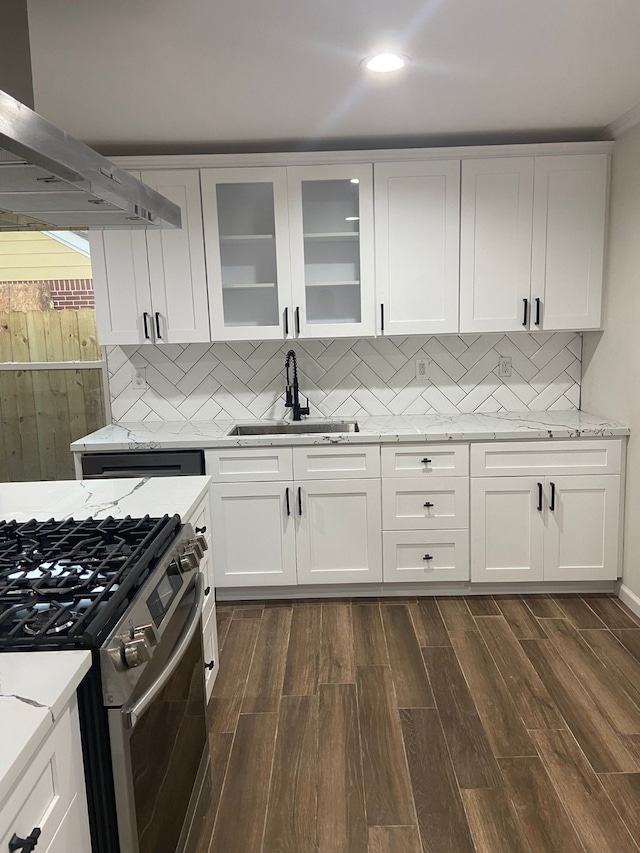 kitchen featuring sink, wall chimney range hood, white cabinets, dark wood-type flooring, and stainless steel gas stove