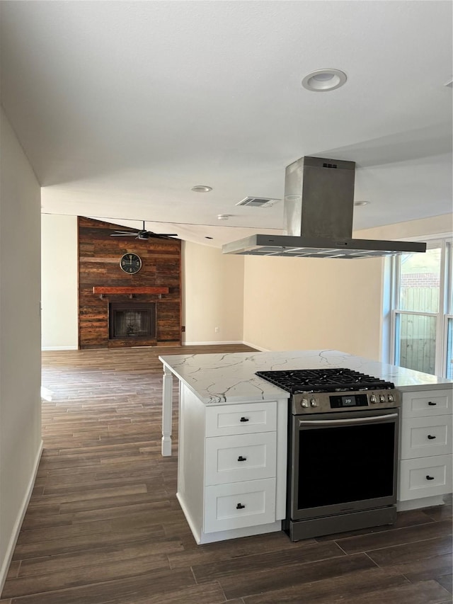 kitchen featuring white cabinets, light stone counters, stainless steel gas range oven, dark hardwood / wood-style floors, and island range hood