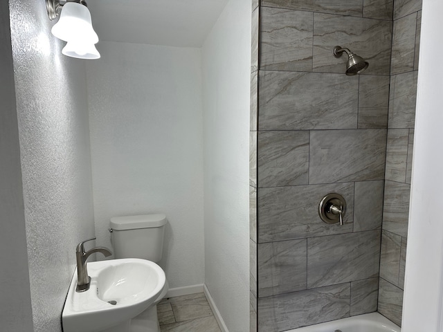 bathroom featuring toilet and tiled shower / bath