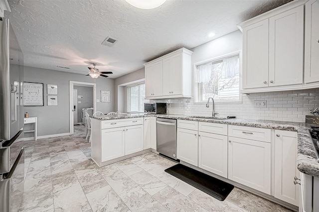 kitchen featuring sink, kitchen peninsula, white cabinets, and appliances with stainless steel finishes