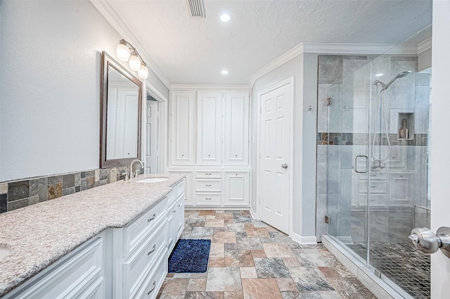 bathroom with a shower with door, a textured ceiling, vanity, and ornamental molding