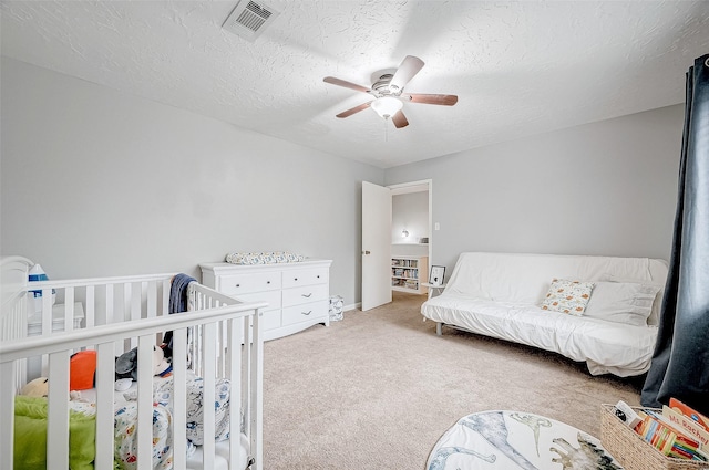 bedroom with ceiling fan, a textured ceiling, and light carpet