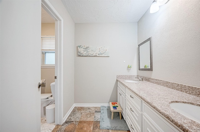 bathroom featuring vanity, toilet, and a textured ceiling