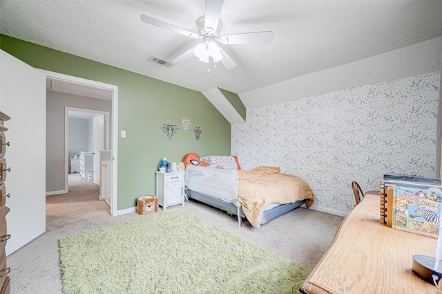 bedroom with lofted ceiling, carpet floors, a textured ceiling, and ceiling fan