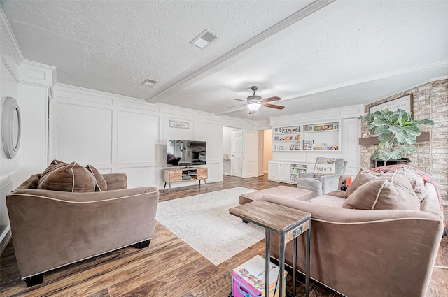 living room with beamed ceiling, hardwood / wood-style floors, a textured ceiling, built in shelves, and ceiling fan