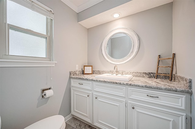 bathroom with toilet, vanity, and crown molding