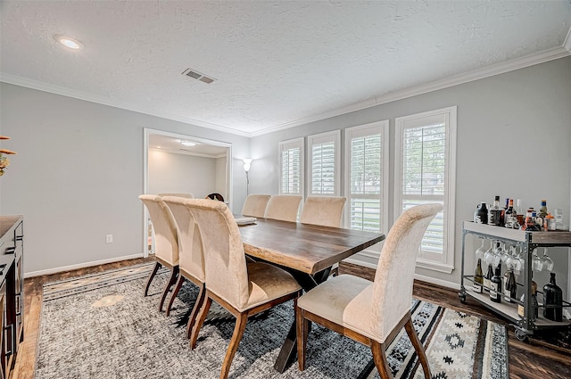 dining space with a textured ceiling, a wealth of natural light, and ornamental molding