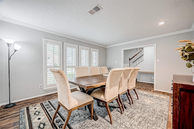 dining room featuring hardwood / wood-style flooring, crown molding, and a textured ceiling