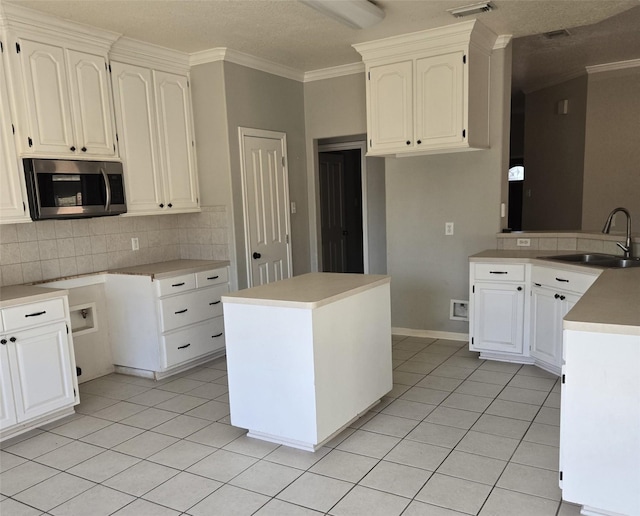 kitchen featuring light tile patterned floors, sink, white cabinets, and a kitchen island