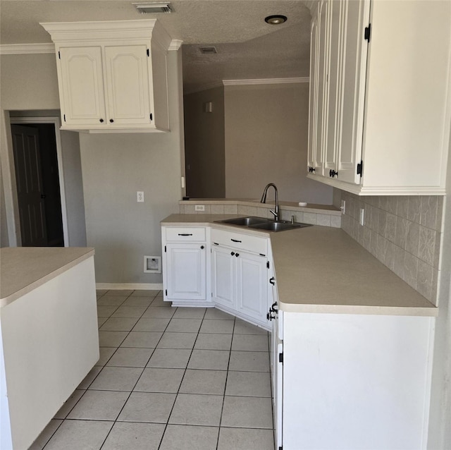 kitchen with kitchen peninsula, sink, white cabinetry, light tile patterned floors, and ornamental molding