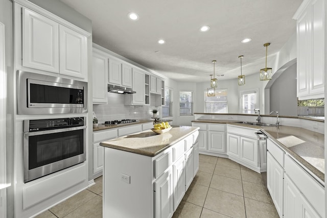 kitchen featuring white cabinets, a kitchen island, stainless steel appliances, hanging light fixtures, and kitchen peninsula