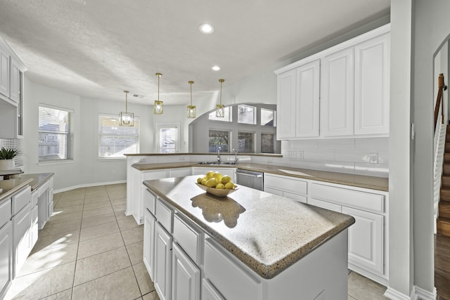 kitchen with white cabinets, a kitchen island, sink, kitchen peninsula, and backsplash