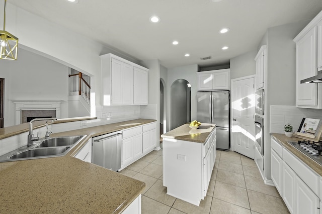 kitchen with sink, appliances with stainless steel finishes, a center island, and tasteful backsplash