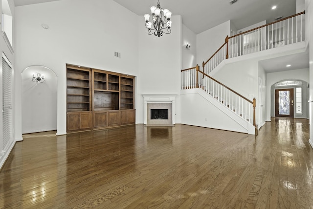 unfurnished living room with a high ceiling, a notable chandelier, and dark hardwood / wood-style flooring