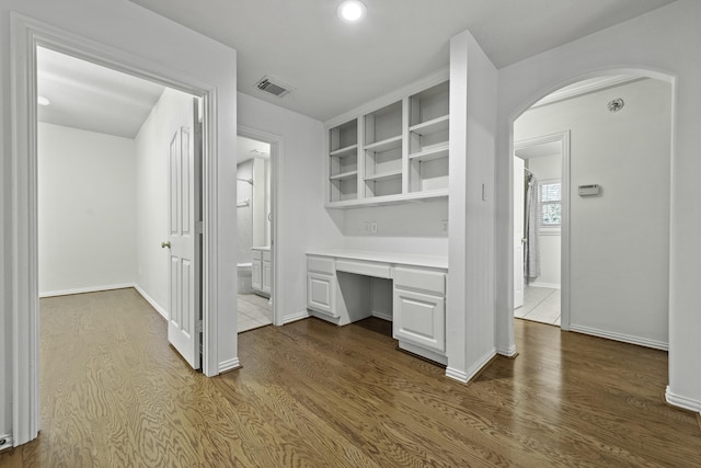 interior space with dark wood-type flooring, white cabinetry, and built in desk