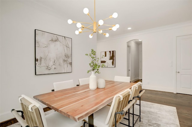 dining area featuring dark wood-type flooring, ornamental molding, and a chandelier