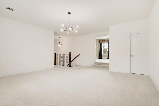 carpeted spare room featuring an inviting chandelier