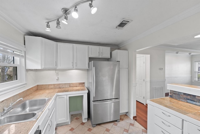 kitchen with sink, white cabinetry, a healthy amount of sunlight, and stainless steel fridge