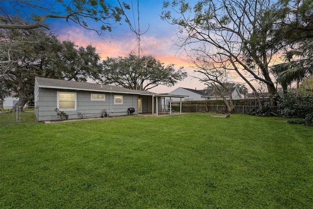 back house at dusk with a lawn