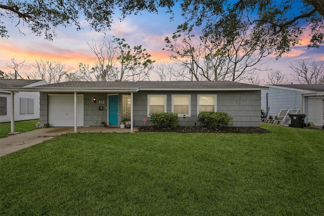 ranch-style house featuring a garage and a yard