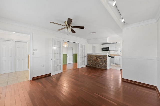 unfurnished living room featuring crown molding, ceiling fan, french doors, dark wood-type flooring, and rail lighting