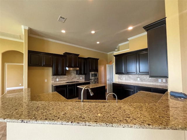 kitchen with decorative backsplash, a center island, and light stone countertops