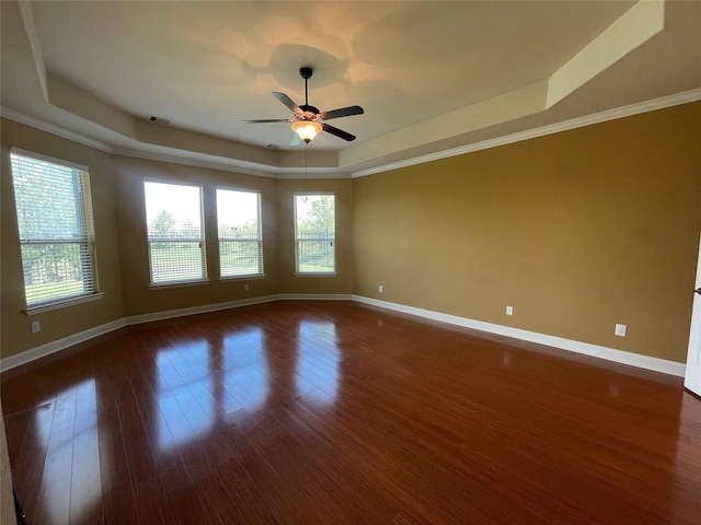 empty room with ceiling fan, a raised ceiling, crown molding, and dark wood-type flooring