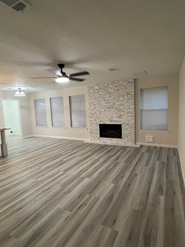 unfurnished living room featuring a fireplace, hardwood / wood-style floors, a textured ceiling, and ceiling fan