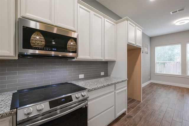 kitchen with stainless steel appliances, white cabinetry, light stone countertops, and tasteful backsplash