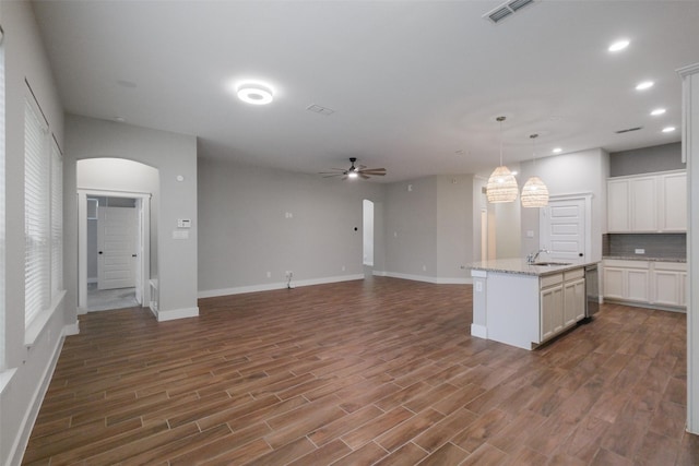 kitchen featuring white cabinets, dishwasher, decorative light fixtures, tasteful backsplash, and a kitchen island with sink