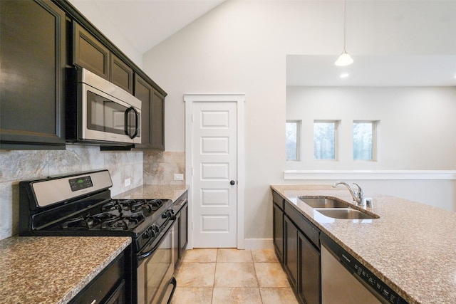 kitchen with appliances with stainless steel finishes, decorative backsplash, sink, pendant lighting, and lofted ceiling