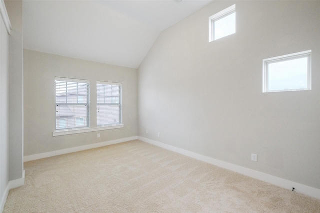 carpeted empty room with vaulted ceiling