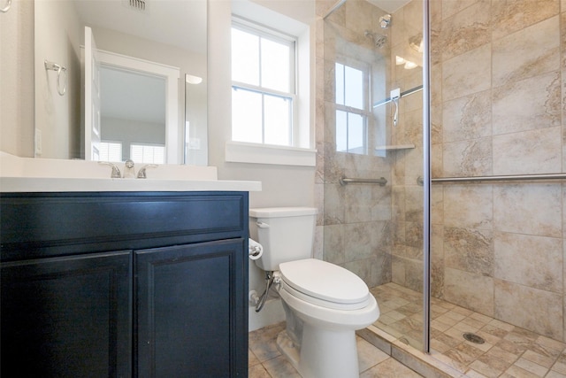 bathroom with toilet, vanity, a tile shower, and tile patterned flooring